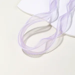 Close-up view of purple organza ribbon with delicate pearl beaded edge detail on white display.