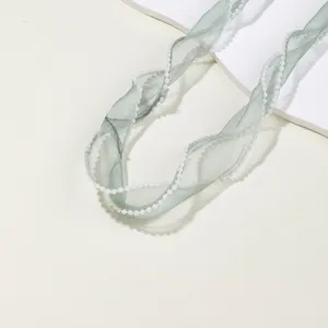 Detailed close-up of sage green organza ribbon with pearl edge, ideal for DIY bows and gifts.