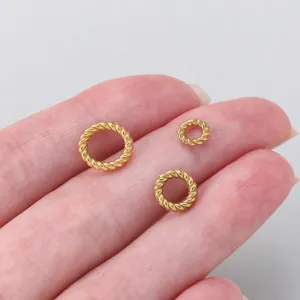 Detail view of twisted gold jump rings on fingers, perfect for DIY jewelry making.
