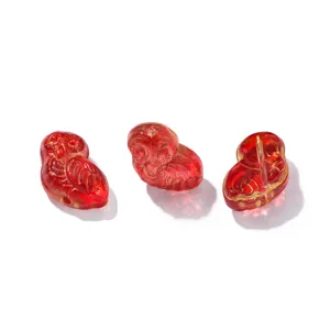 Gros plan de perle hibou translucide rouge, breloque artisanale DIY en cristal doré