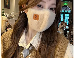 Primer plano de la mascarilla facial de invierno de felpa suave en crema con detalle de cuero.