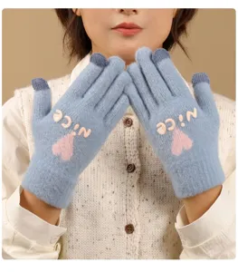 Close-up detail of soft knit winter touchscreen gloves in light blue with cute pink heart.