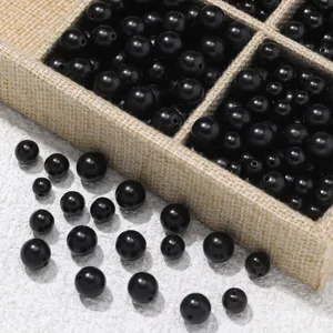Black wooden loose beads for DIY jewelry making, closeup detail view in fabric storage box.