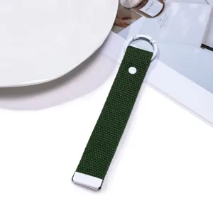 Dark green woven keychain strap with snap button detail, close-up view of portable bag accessory.