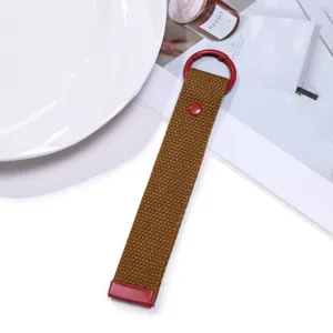 Close-up detail of the brown woven webbing keychain with red metal hardware and snap button.
