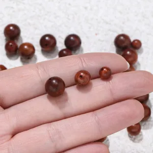 Close-up detail shot of natural padauk wooden loose round beads in various sizes for DIY craft.