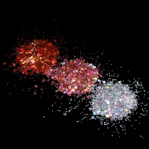 Close up detail of holographic nail glitter sequins in red pink and silver sparkling particles.