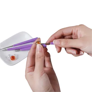 Primer plano detallado de la herramienta de escariado de cuentas y taladro manual para joyas de cristal.