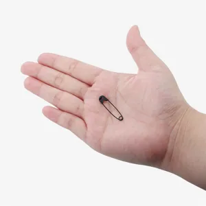 Close-up detail of a small black safety pin displayed on hand, showing size and texture.