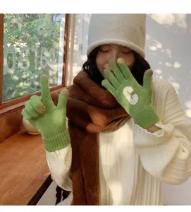 Close-up view of green knitted touchscreen gloves featuring white letter C design for winter.