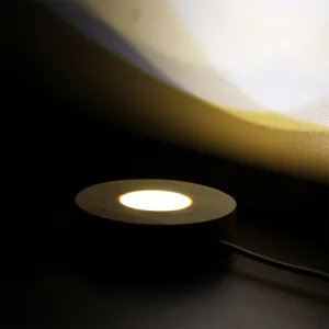 Vue detaillee de la base lumineuse ronde en bois pour boule de cristal et veilleuses LED.