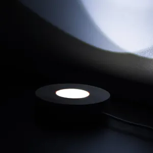Socle d'affichage lumineux LED en bois vue de detail montrant la lumiere chaude et le cable.