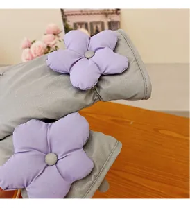 Close-up detail of winter thick warm gloves, grey fabric with purple 3d floral decor.