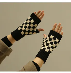 Detailaufnahme von schwarz-weißen Karo Strick Fingerlosen Handschuhen für den Winter.