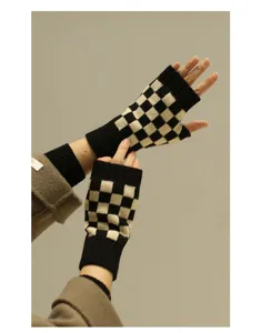 Detailaufnahme von schwarz-weißen karierten, fingerlosen Strickhandschuhen mit Rippbündchen.
