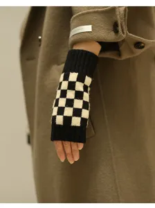 Nahaufnahme von schwarz-weißen karierten Strick-Fingerlingen an der Hand getragen.