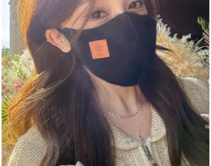 Primer plano detallado de una mascarilla facial de invierno de lana negra con parche naranja.