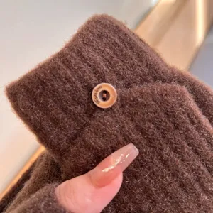 Detailed close-up view of brown knitted winter warm gloves featuring vertical stripes and button.