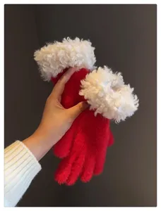 Close-up detail of winter red fuzzy gloves with white fluffy trim, soft and warm touch.