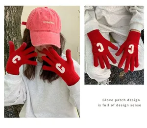 Detailed close-up view of winter warm red knitted gloves featuring white letter C.