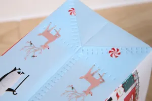Detailed view of a light blue Christmas gift bag with cute reindeer and candy prints.