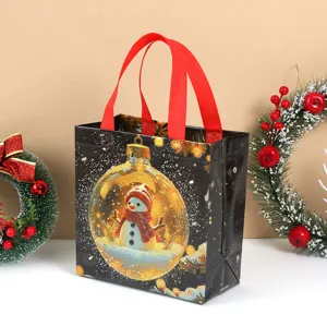 Detailed view of black non-woven Christmas gift bag with festive snowman print and red handles.