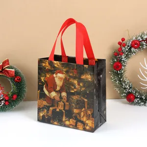 Detail shot of black Christmas tote bag featuring Santa Claus and red handles for holiday.
