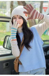 Close-up detail of winter warm knitted striped touch screen gloves and beanie hat outdoor.