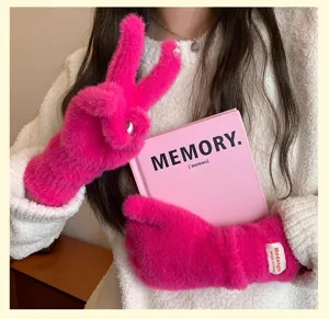 Primer plano de guantes cálidos y suaves de felpa rosa vivo con dedos separados, pelo sintético.