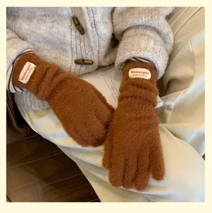 Vista de detalle cercana de guantes de invierno de punto suave y esponjosos en marrón con etiqueta.