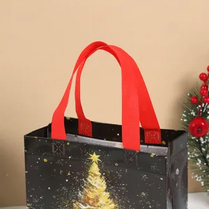 Detail view of black Christmas non-woven gift bag featuring gold tree and red handles.