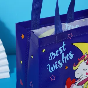 Detailed view of dark blue non-woven gift bag featuring cute unicorn and star print.