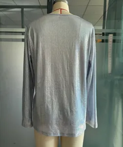 Détail de dos d'un pull à manches longues brillant argenté, tissu métallique élégant.
