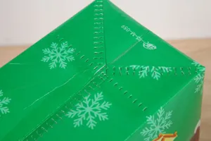 Green Christmas non-woven gift bag featuring festive white snowflake patterns for holiday gifting.