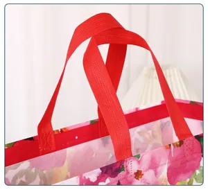 Detailed view of floral non-woven gift packaging bag with red handles for shopping and storage.