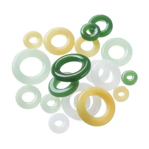 Primer plano de varios anillos coloridos de vidrio y jade imitación para accesorios de joyería.