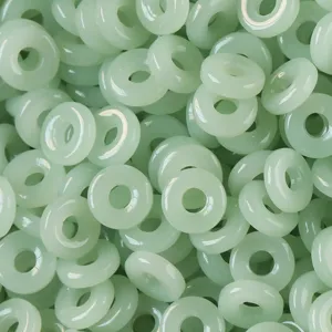 Vista detallada de cuentas de anillo de vidrio verde claro imitación jade para joyería.