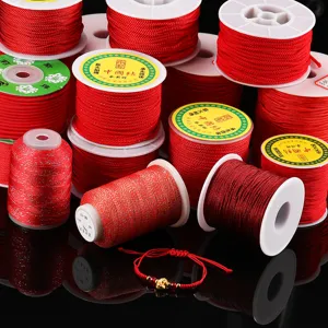 Vue détaillée des cordons en nylon rouge, fils pailletés et fils métalliques dorés pour bricolage.