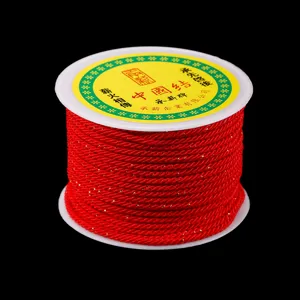 Détail de bobine de fil de nylon rouge, tissage fil d'or, parfait pour bijoux et loisirs créatifs.