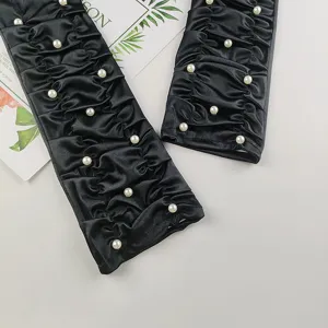Vue détaillée de longs gants noirs en satin froncé ornés de perles élégantes.