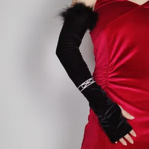 Detailed view of long black velvet gloves with feather trim and rhinestone bow for evening party.