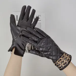 Close-up of women black PU leather winter gloves with chic quilting and gold chain cuff.