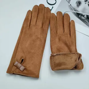 Detail close-up of brown winter fleece-lined suede gloves featuring a cute bow decoration.