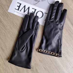 Detailansicht eleganter schwarzer Lederhandschuhe für Damen mit goldener Kettenmanschette.