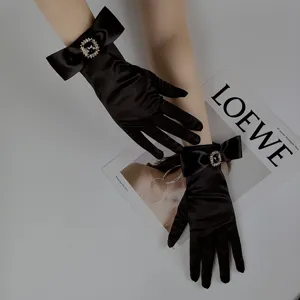 Black satin bridal evening gloves with rhinestone bow detail, elegant accessory for photos.
