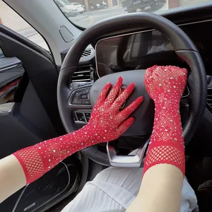 Close-up of red fishnet mesh gloves adorned with sparkling rhinestones, worn inside a car.
