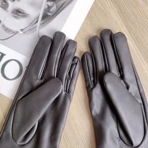 Nahaufnahme von dunkelgrauen Damen Lederhandschuhen mit strukturierter Handfläche und warmem Futter.