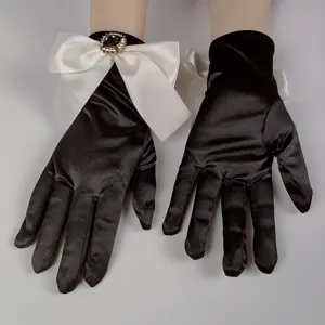 Vista di dettaglio di guanti in satin nero in stile vintage con fiocco bianco e spilla di strass.