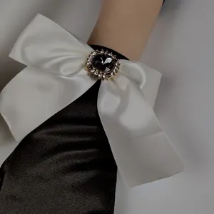 Guanti in satin nero vintage con elegante fiocco bianco e accessorio di strass scintillante.