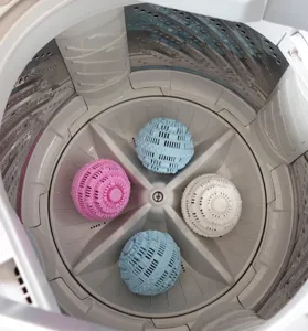 Detailed view of colorful TPR laundry balls inside washing machine, anti-tangle cleaning tool.